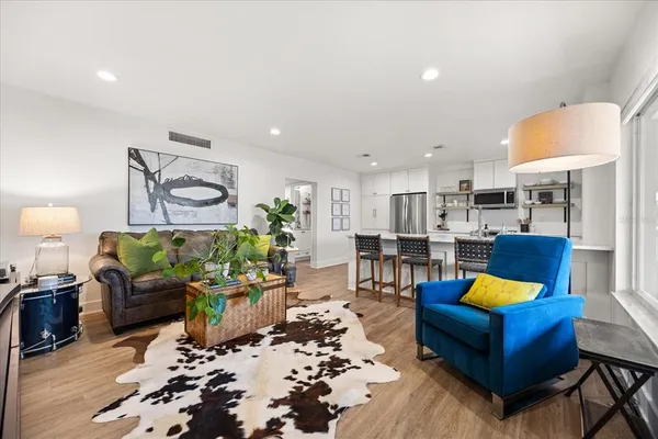 a living room with furniture kitchen view and a lamp
