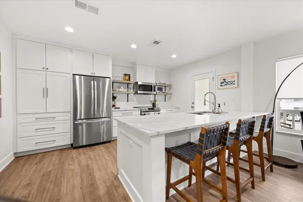 a kitchen with stainless steel appliances a refrigerator a stove a sink and white cabinets with wooden floor