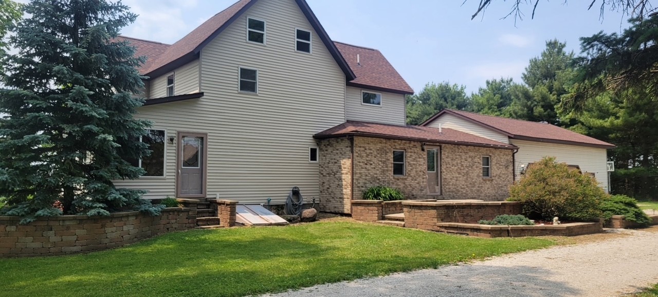 382 Keigwin Road Walnut, IL 61376 - Photo 2 of 49 a view of a white house next to a yard with plants and large tree