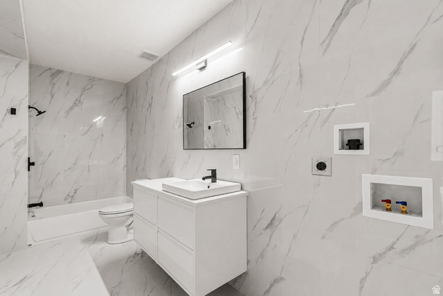 1429 Chateau Ridge Way Sandy, UT 84092 - Photo 12 of 22 Bathroom featuring full-height marble-style tiling, a white floating vanity with an integrated sink, and matte black plumbing fixtures