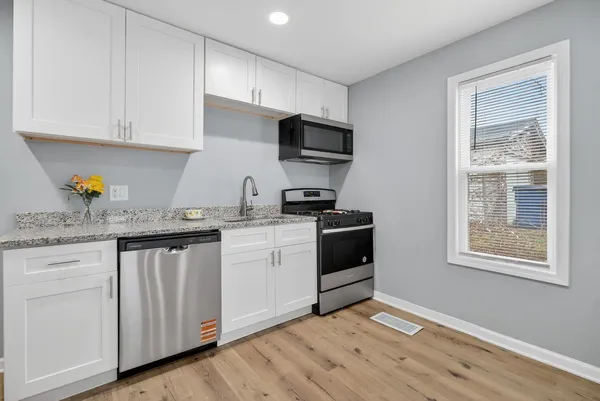 a kitchen with granite countertop white cabinets and stainless steel appliances