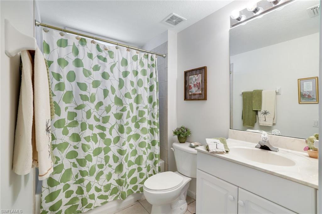 10049 Heather Lane, Unit 101 Naples, FL 34119 - Photo 23 of 28 Full bath featuring vanity, light tile patterned flooring, and shower / bath combination with curtain