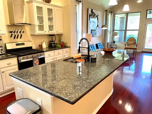 a kitchen with stainless steel appliances granite countertop a sink a stove and a wooden cabinets