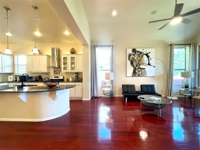 a living room with furniture kitchen view and a wooden floor
