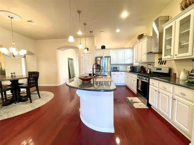 a kitchen with stainless steel appliances granite countertop a stove a sink dishwasher a dining table and chairs with wooden floor