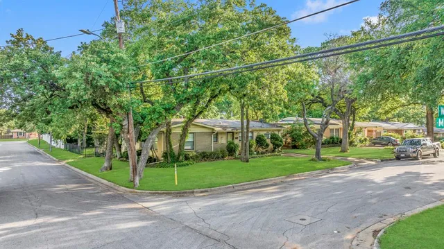 a view of a house with a big yard and large trees