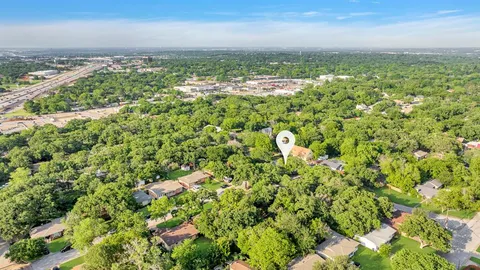 an aerial view of residential houses with outdoor space and trees