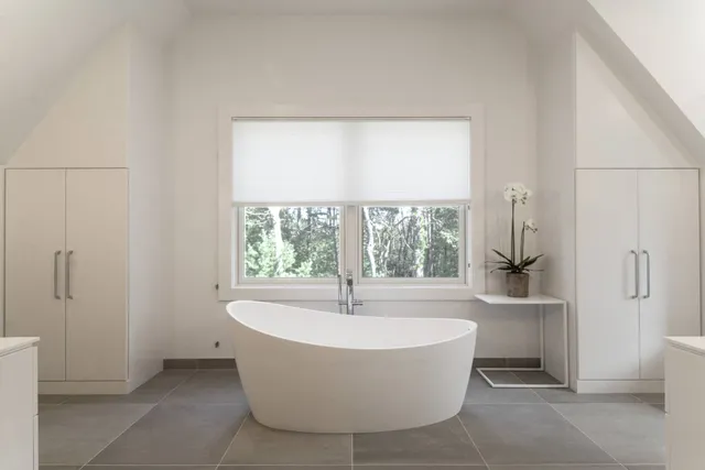 a white bath tub sitting in a bathroom next to a window