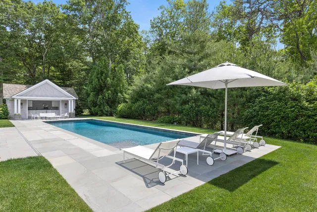 a view of house with backyard outdoor seating and trees in the background