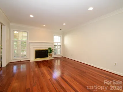 a view of an empty room with wooden floor and a fireplace
