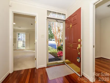 a view of a hallway with wooden floor and a bathroom