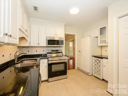 a kitchen with granite countertop white cabinets and white appliances