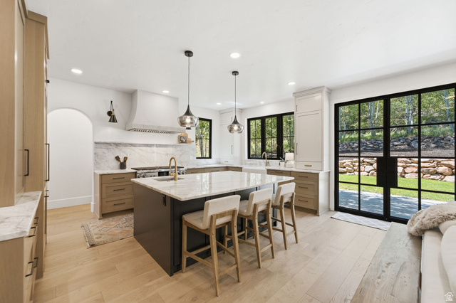 3027 Homestead Road Park City, UT 84098 - Photo 10 of 62 Well-appointed kitchen featuring a large central island with seating, light wood-finish flooring, and a marble backsplash