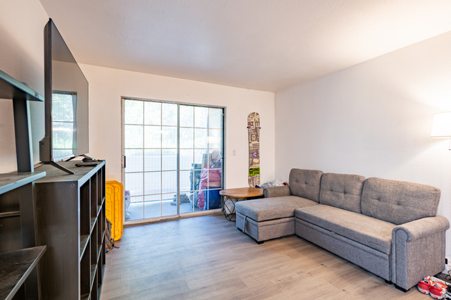 1221 Waterside Cove, Unit 11 Midvale, UT 84047 - Photo 4 of 23 Spacious room featuring light wood-finish flooring, white painted walls, and a large grid-patterned sliding glass door opening to an exterior area