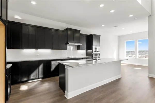 a kitchen with stainless steel appliances kitchen island granite countertop a stove a sink and a microwave