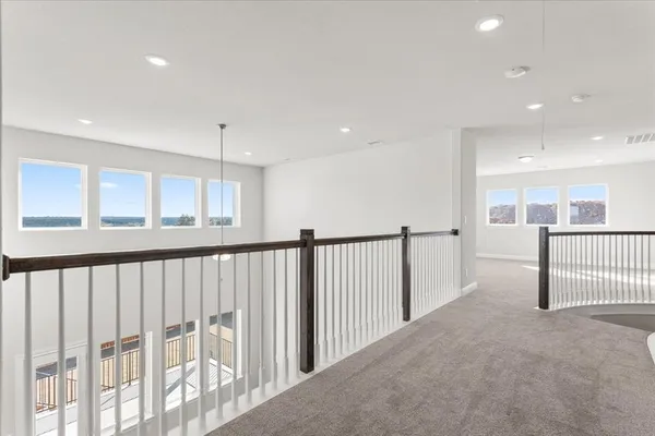 a view of an empty room with wooden floor and chandelier