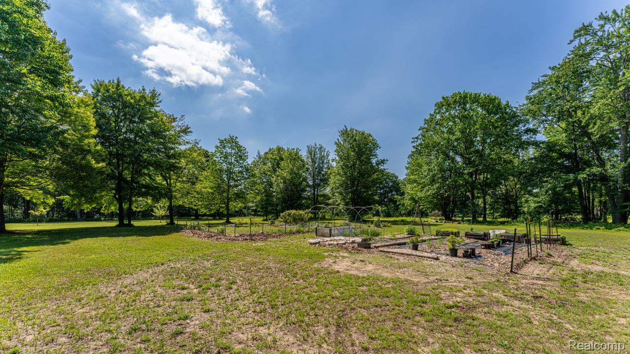 2418 South 41st Road South Cadillac, MI 49601 - Photo 54 of 57 Expansive outdoor space featuring a garden area with raised beds, surrounded by a large grassy lawn and mature trees