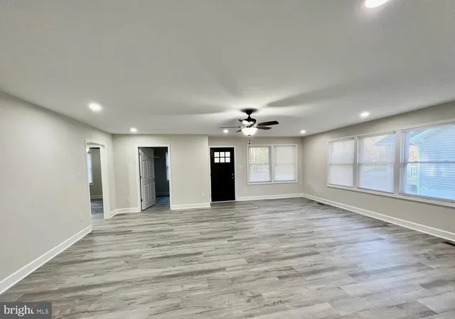 a view of an empty room with a window and wooden floor