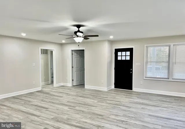 a view of an empty room with window and wooden floor