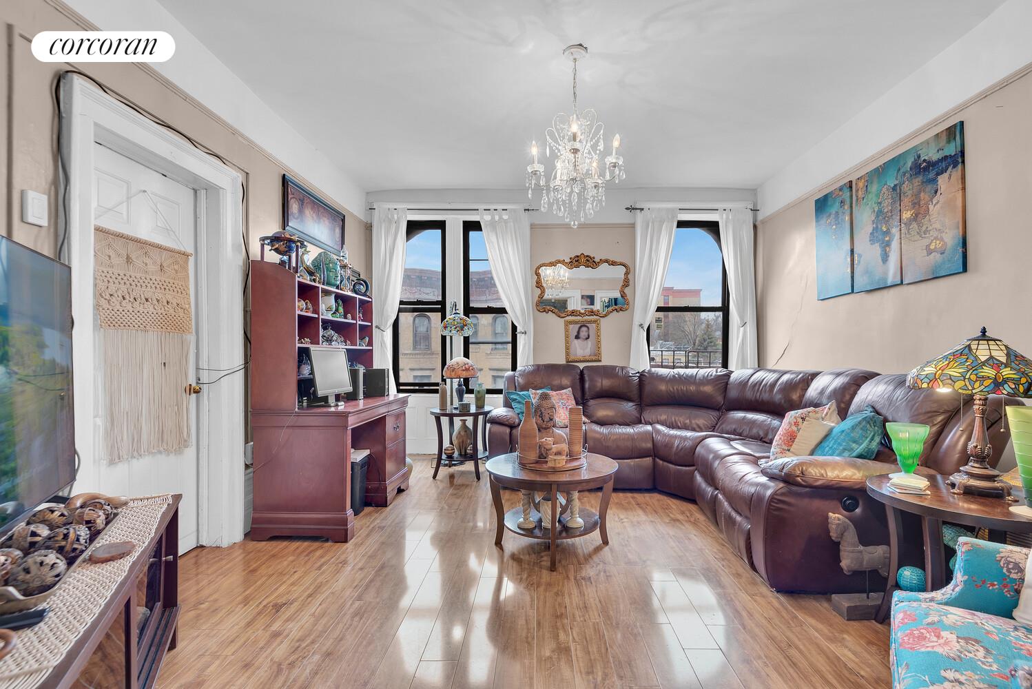 a living room with furniture chandelier and wooden floor