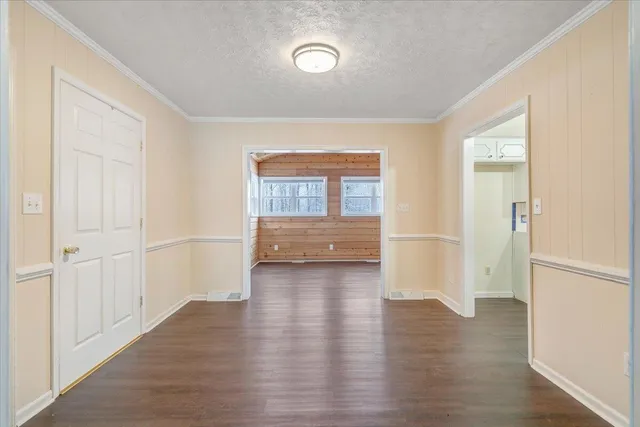 a view of a kitchen and an empty room with wooden floor