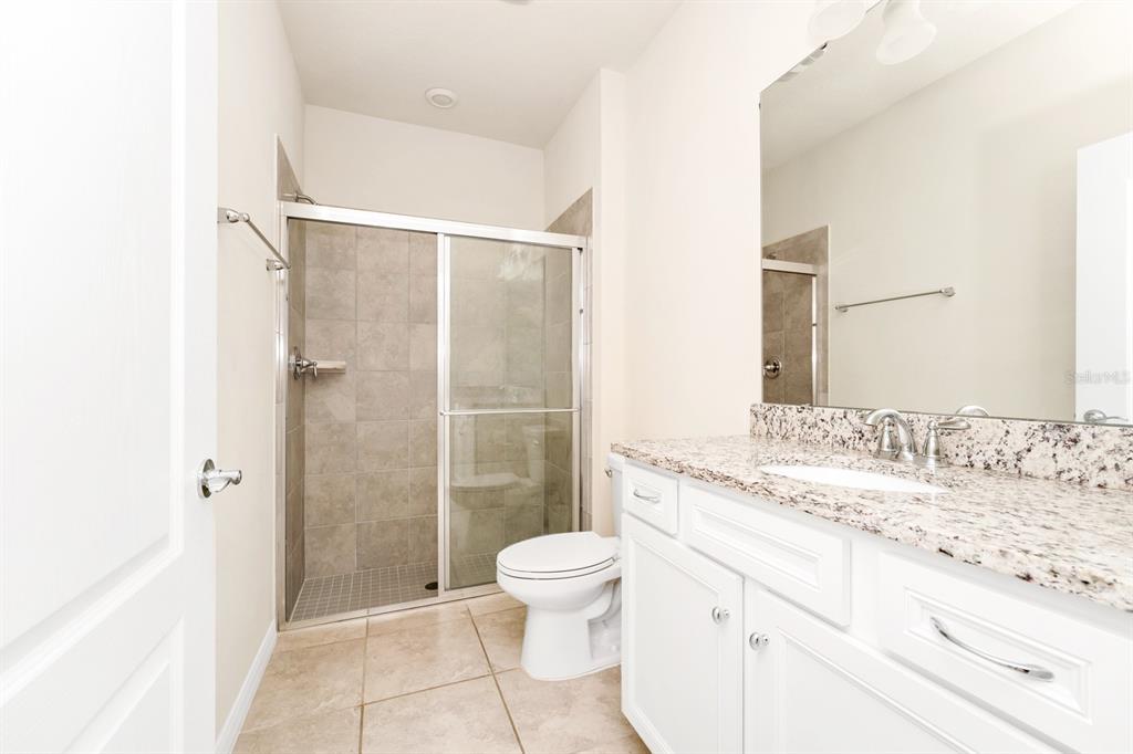 7513 Oak Spring Lane Davenport, FL 33837 - Photo 12 of 40 a bathroom with a granite countertop sink toilet and shower