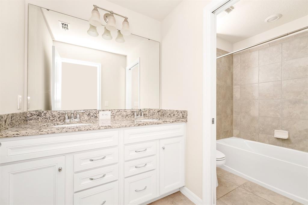 7513 Oak Spring Lane Davenport, FL 33837 - Photo 16 of 40 a bathroom with a granite countertop sink mirror and a bathtub