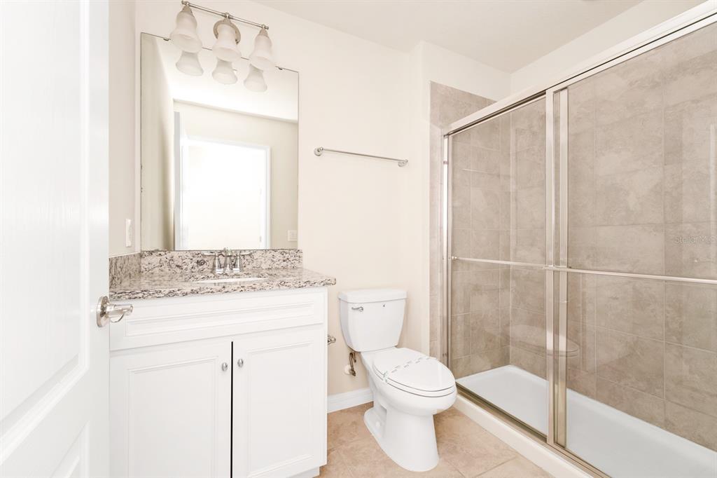 7513 Oak Spring Lane Davenport, FL 33837 - Photo 22 of 40 a bathroom with a granite countertop sink toilet and shower