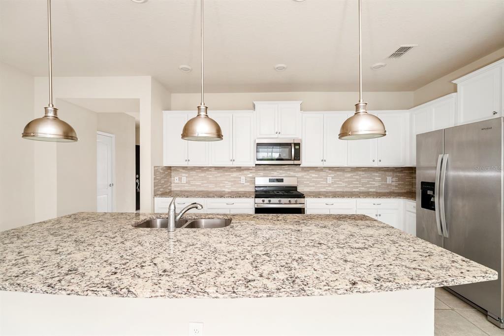 7513 Oak Spring Lane Davenport, FL 33837 - Photo 5 of 40 a kitchen with stainless steel appliances granite countertop a sink a stove and a refrigerator