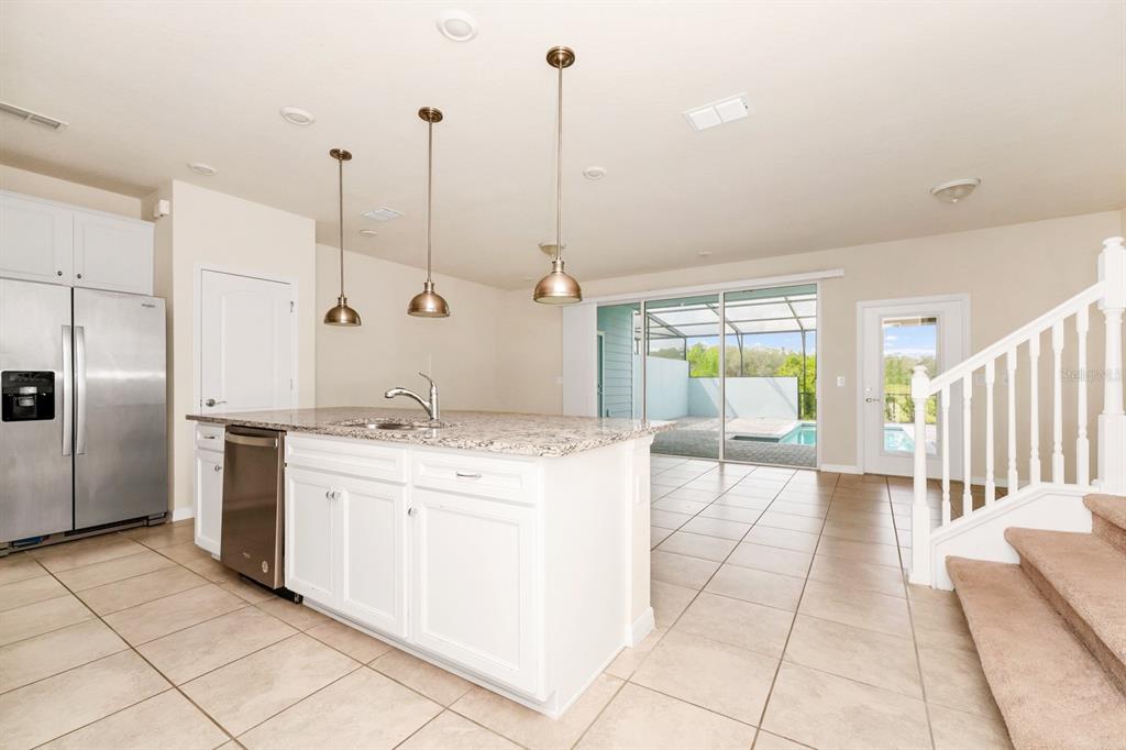 7513 Oak Spring Lane Davenport, FL 33837 - Photo 7 of 40 a kitchen with stainless steel appliances kitchen island granite countertop a stove a sink and a refrigerator