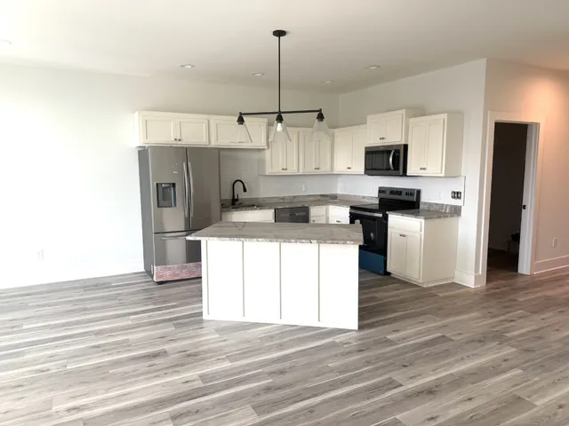 a kitchen with stainless steel appliances kitchen island granite countertop a refrigerator a stove top oven a sink and dishwasher