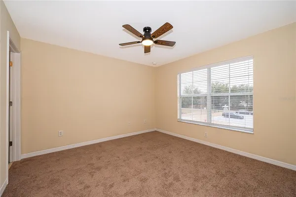 an empty room with ceiling fan and window