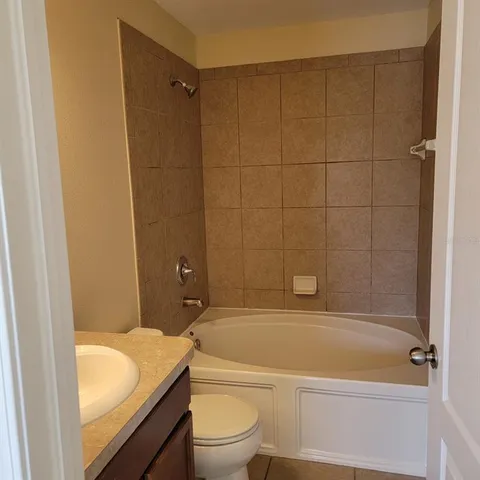 a bathroom with a granite countertop bathtub shower sink vanity and toilet