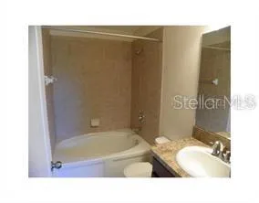 a bathroom with a tub sink vanity and toilet