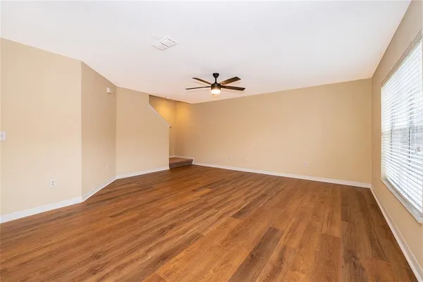 an empty room with wooden floor and windows