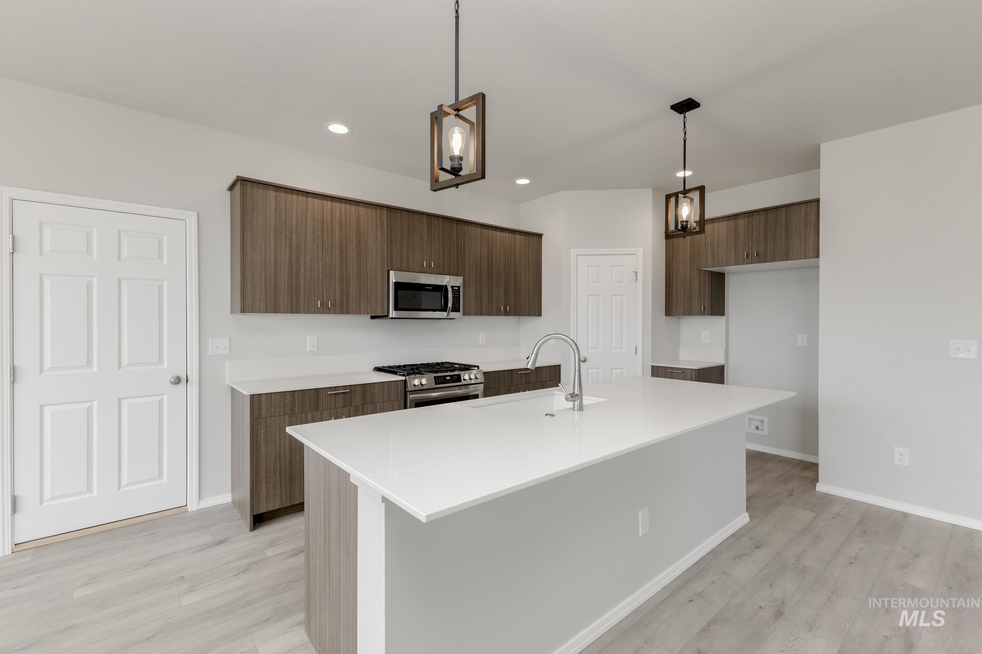12842 Ropers Street Nampa, ID 83651 - Photo 3 of 29 Kitchen featuring a large island with an integrated sink, stainless steel appliances, wood-finish cabinetry, and recessed lighting