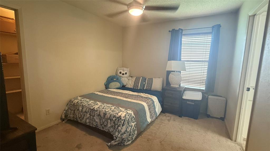 1356 Kerry Lane Azle, TX 76020 - Photo 15 of 27 Carpeted room featuring a ceiling fan with integrated lighting, a window with blinds, and an open doorway revealing a closet with built-in shelving