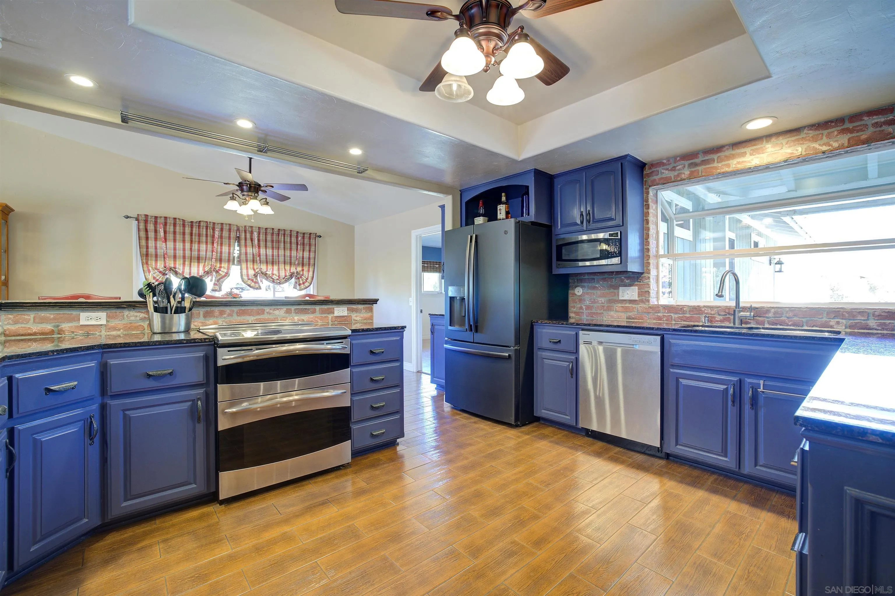15835 Mactan Road Valley Center, CA 92082 - Photo 12 of 31 a kitchen with stainless steel appliances granite countertop a refrigerator a sink dishwasher a stove and a dining table with wooden floor