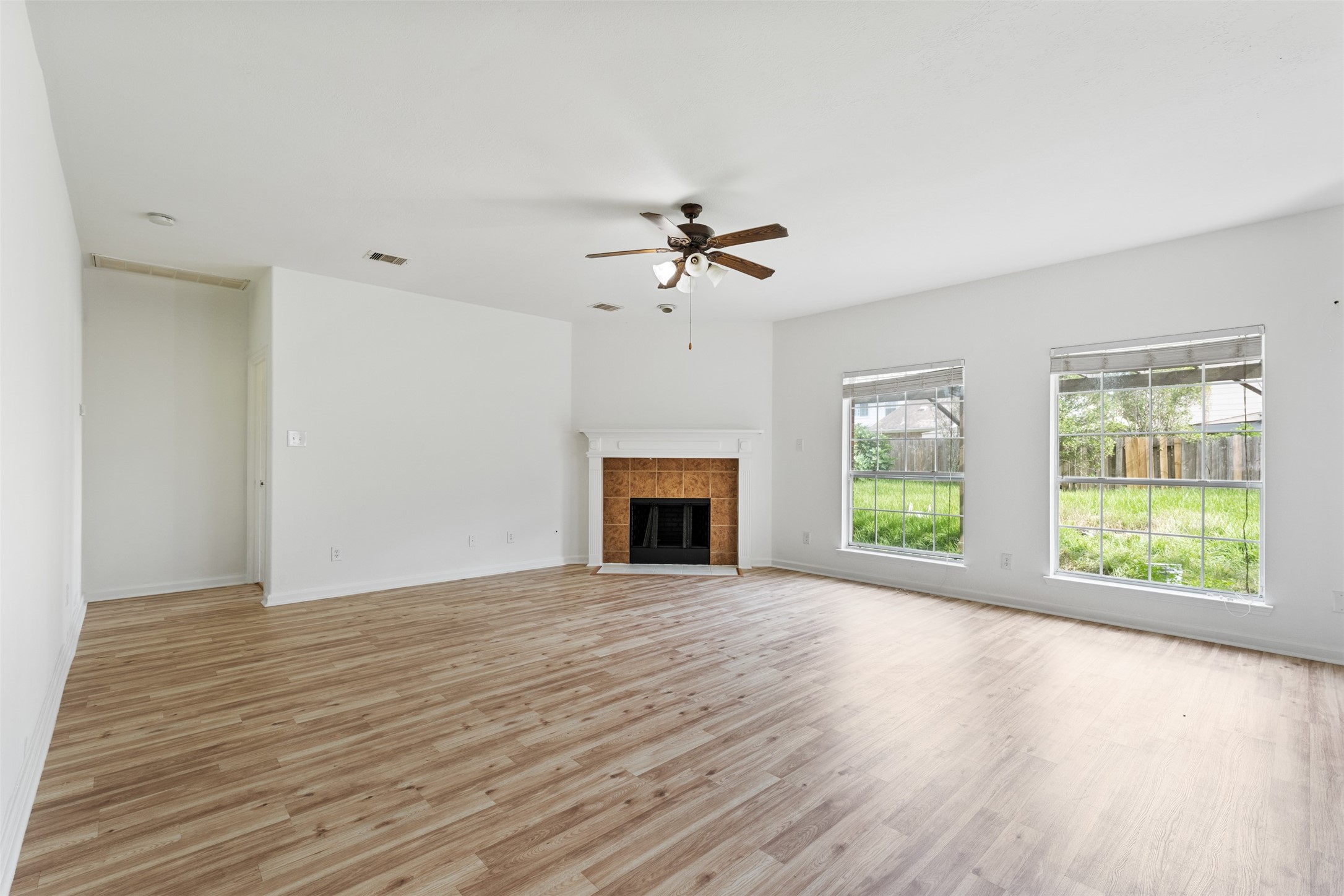 6806 Stableton Lane Houston, TX 77049 - Photo 44 of 50 an empty room with windows fireplace and a ceiling fan