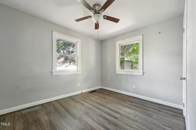 an empty room with wooden floor and a ceiling fan