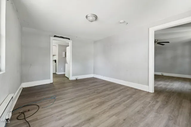 an empty room with wooden floor and windows