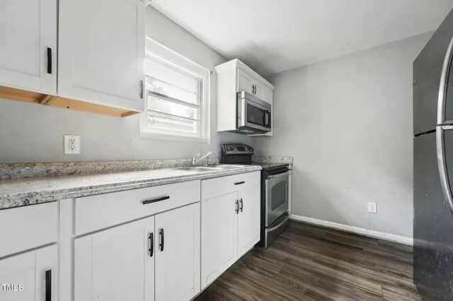 a kitchen with granite countertop cabinets stainless steel appliances and a window