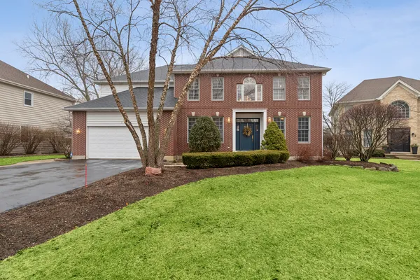 a view of a brick house with a yard and large tree