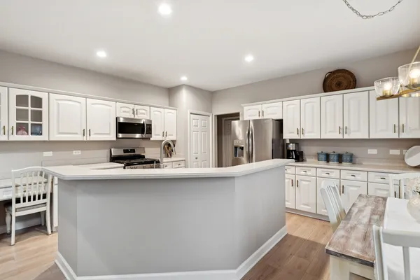 a kitchen with stainless steel appliances a sink a stove a refrigerator cabinets and a window