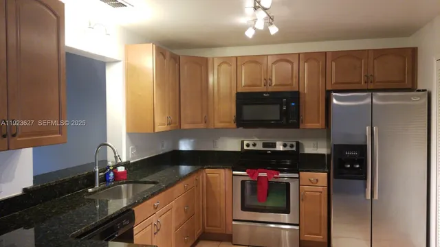 a kitchen with granite countertop a refrigerator stove and sink