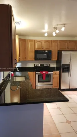 a kitchen with stainless steel appliances granite countertop a sink a stove a microwave a counter top and cabinets