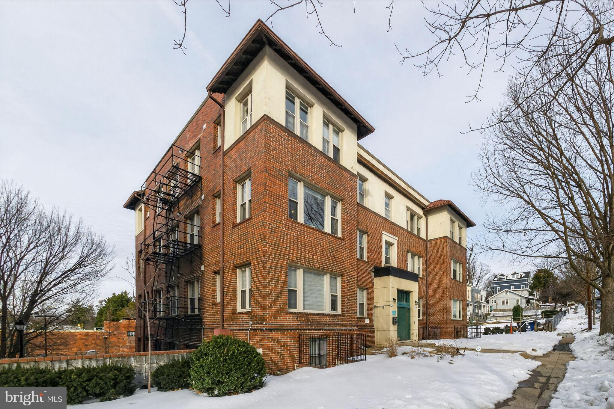 a front view of a building with lot of cars and trees