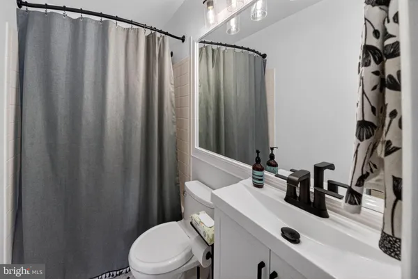 a bathroom with a sink a toilet a mirror and shower curtain