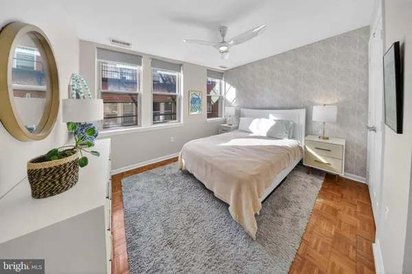 a bedroom with a bed a mirror on dresser and a window