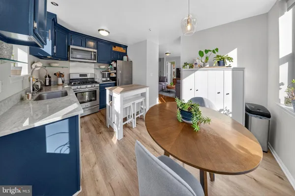 a kitchen with stainless steel appliances kitchen island granite countertop a refrigerator a stove and a sink with wooden floor